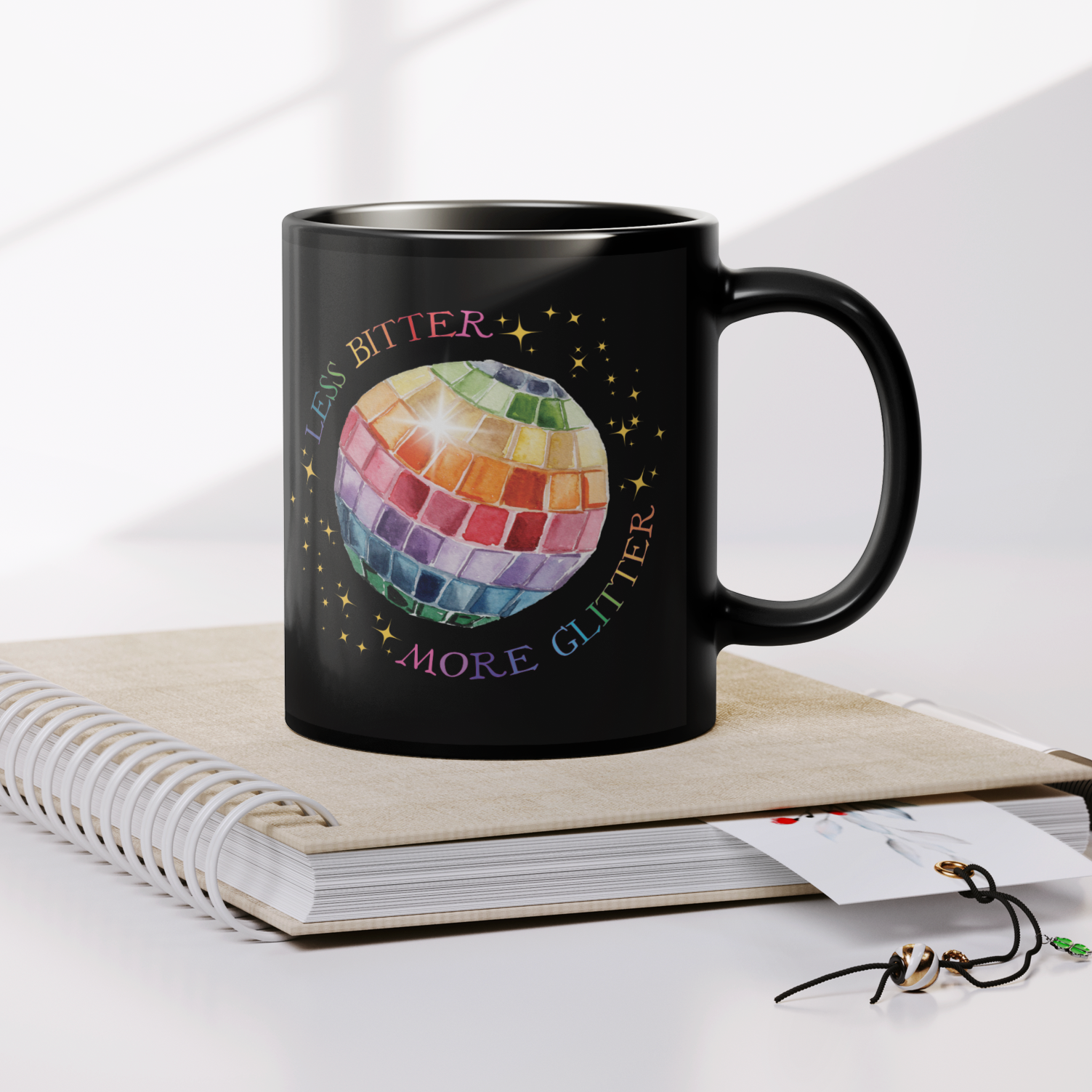 Less_Bitter_More_Glitter_Black_11oz_Mug_Lifestyle_Notebook_Mockup.png